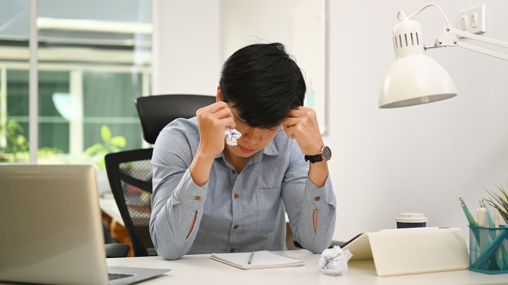 Frustrated businessman looking information on paperwork and crumpled paper.